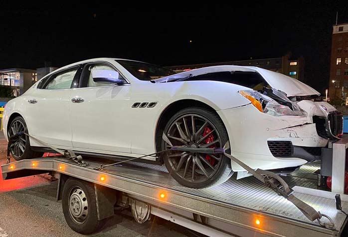 damaged white maserati recovered after a car accident on the road
